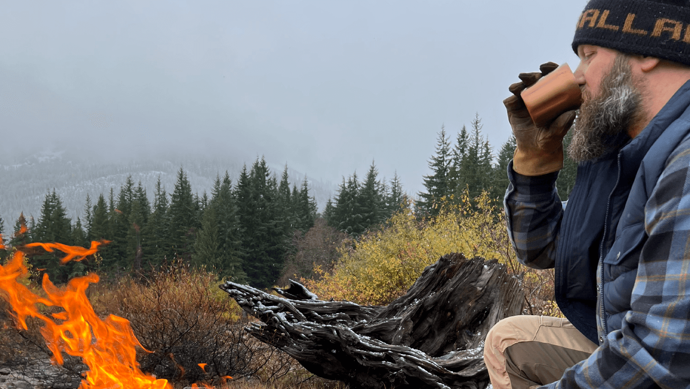 Backpacker drinking best whiskey out of Firelight Flask near the fire