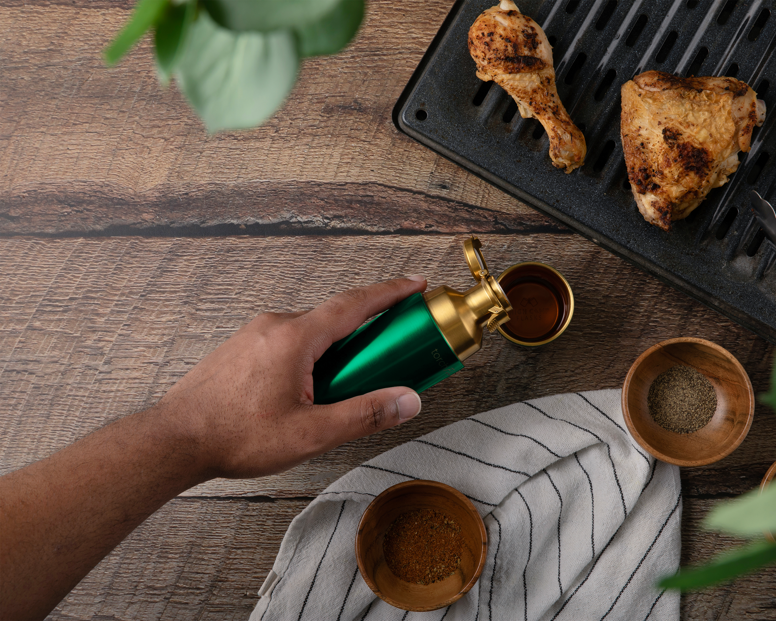 Hand pouring a liquid from a green and gold bottle.